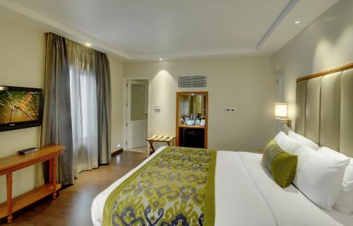 a hotel room with a large bed and a television at Lemon Tree Premier “The Atrium” Ahmedabad in Ahmedabad