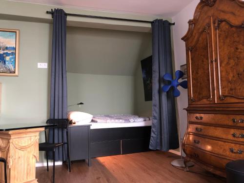 a bedroom with a bed with blue curtains and a dresser at Gästewohnung im Logenhaus in Mainz
