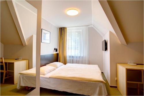 two pictures of a bedroom with a bed and a window at Hotel Jurate in Nida