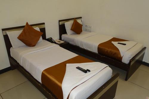 two beds in a hotel room with a remote control on them at Hotel Sunshine Airport in Mumbai
