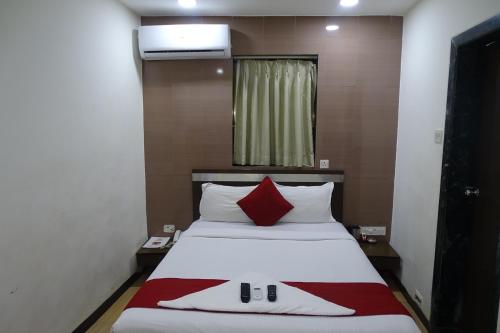 a bedroom with a large bed with a red pillow at Hotel Sunshine Airport in Mumbai
