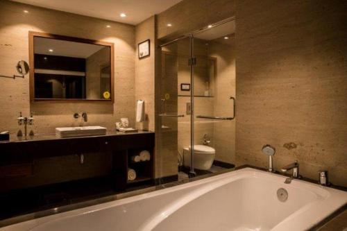 a bathroom with a tub and a toilet and a sink at Lemon Tree Hotel Siliguri in Siliguri