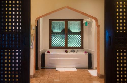 a bathroom with a tub and a window at Amani Beach Resort in Kutani