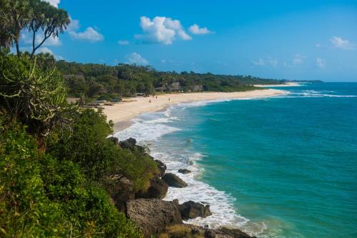 a beach with people walking on the sand and the ocean at Amani Beach Resort in Kutani