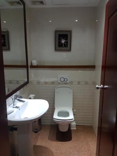 a bathroom with a sink and a toilet and a mirror at Grand Legacy Hotel in Kigali