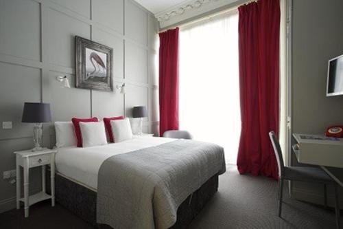 a hotel room with a bed and a desk and a window at Georgian House Hotel in London