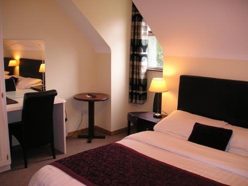 een hotelkamer met een bed, een bureau en een spiegel bij Mountain View Guesthouse in Oughterard