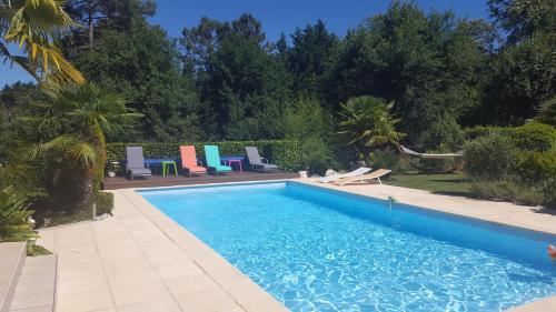 une piscine avec des chaises colorées à côté d'une cour dans l'établissement Le Mas des Geais, à Atur