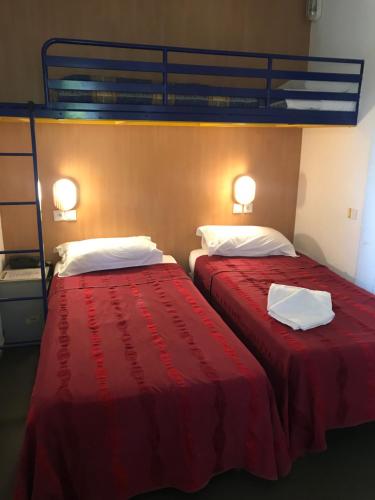 two beds sitting next to each other in a room at Hôtel Noctuel Blois Sud in Saint-Gervais-la-Forêt