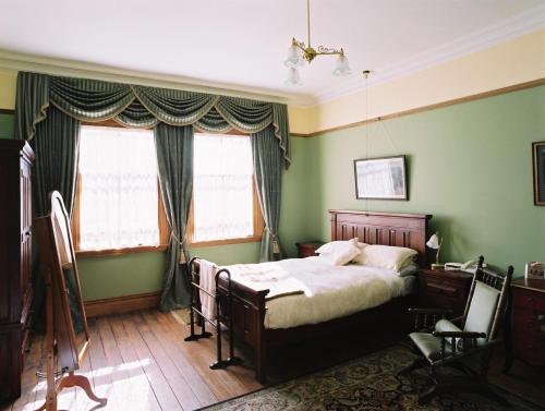 a bedroom with a bed and two windows at Braemar On Parliament St in Auckland