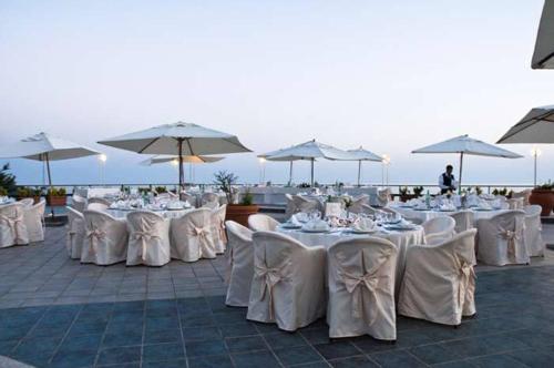 a group of tables with white chairs and umbrellas at Hotel Club San Diego in Maratea