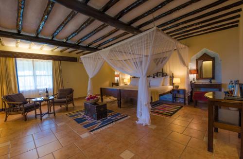 a bedroom with a canopy bed in a room at Amani Beach Resort in Kutani