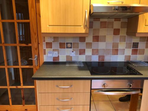 a kitchen with wooden cabinets and a counter top at Rona in Aultgrishin