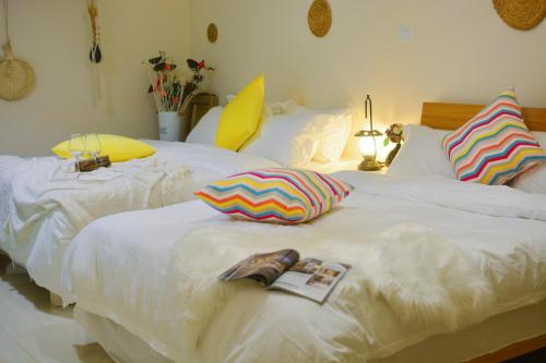 two white beds with pillows and a magazine on them at YoYo Youth Apartment in Guangzhou