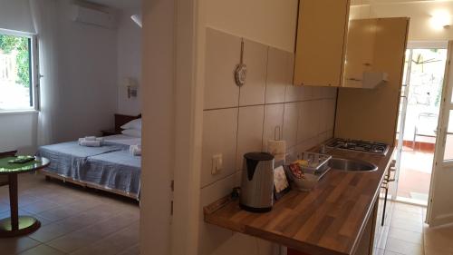 a kitchen with a sink and a bed in a room at Guest House Sol in Cavtat
