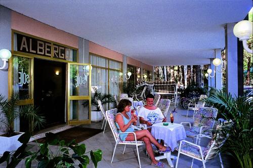 a man and woman sitting at a table on a patio at Hotel Sole in Rosolina Mare