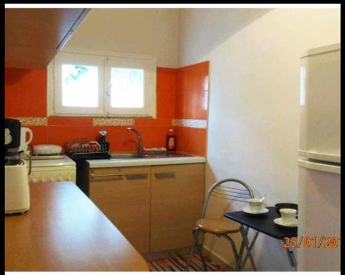 een keuken met oranje muren, een wastafel en een tafel bij Sea view house on Poros in Poros