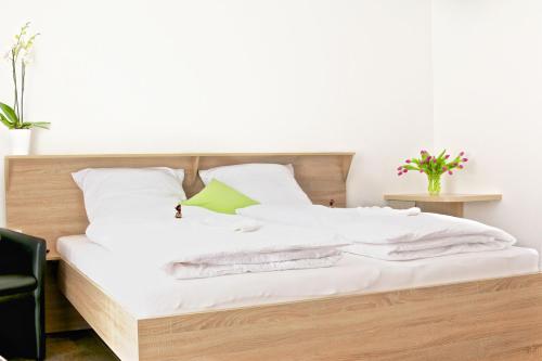 a bed with white sheets and a green pillow at Alte Stadtmauer - Apartment in Sinsheim