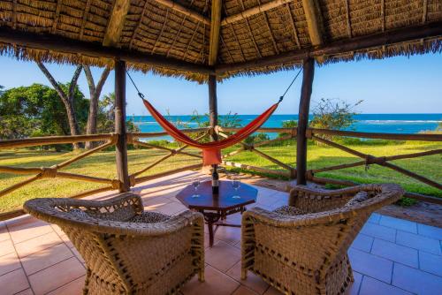 a patio with a table and chairs and a view of the ocean at Amani Beach Resort in Kutani
