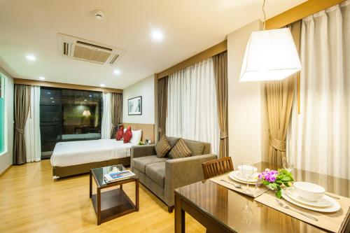 Habitación de hotel con cama y sala de estar. en Burgundy Residence 304, en Si Maha Phot