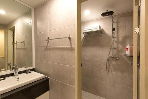 a bathroom with a shower and a sink and a mirror at Cheonjiyeon Crystal Hotel in Seogwipo