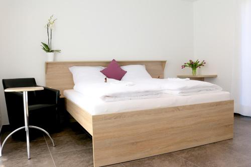 ein Bett mit weißer Bettwäsche und einem Stuhl in einem Zimmer in der Unterkunft Alte Stadtmauer - Apartment in Sinsheim