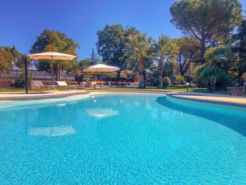 a large swimming pool with blue water and umbrellas at B&B Blanc Maison Etna Relais & Charme in Nicolosi