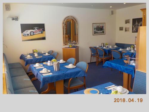 ヴォルフスブルクにあるポルシェ ホテルの青いテーブルと椅子、壁に車が並ぶレストラン