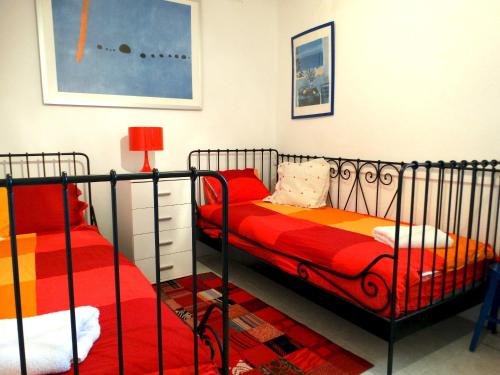 サン・フェリウ・デ・ギホルスにあるDAN, MARAVILLOSA CASA VERANIEGA A POCOS MINUTOS DEL MAR CON PISCINA Y WIFIの赤とオレンジのシーツが備わるベッドルームのベッド2台