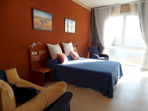 サンタ・クリスティーナ・ダロにあるLES TEULES, MAGNIFICA CASA EN URBANIZACION TRANQUILA CON PISCINA PRIVADA Y WIFI GRATUITOのオレンジ色の壁のベッドルーム1室、ベッド1台、ソファが備わります。