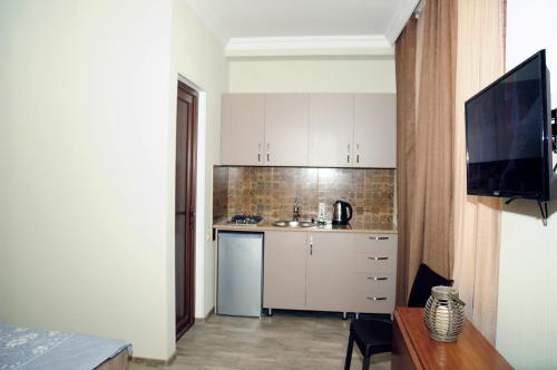 a small kitchen with white cabinets and a television at Nimako's Apartment in Borjomi