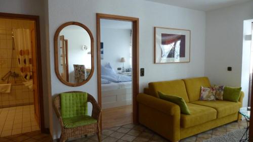 a living room with a yellow couch and a mirror at Ferienwohnung Ute in Kandern