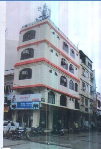 a tall white building with a clock on top of it at D.C hotel in Chittaurgarh