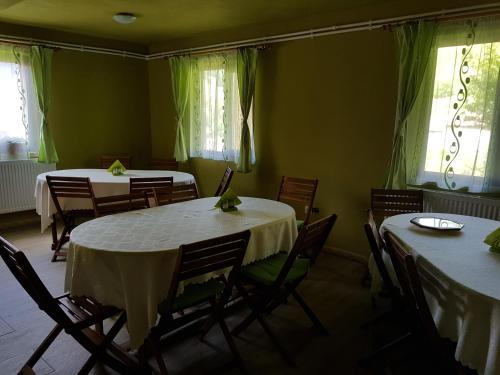 Flower Bell في Ghimeş-Făget: غرفة طعام مع طاولات وكراسي ونوافذ