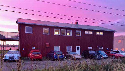 a group of cars parked in front of a red building at Midnattsol rom og hytter in Bleik