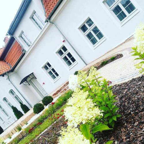 a white house with flowers in front of it at Willa Park Apartamenty in Olsztyn