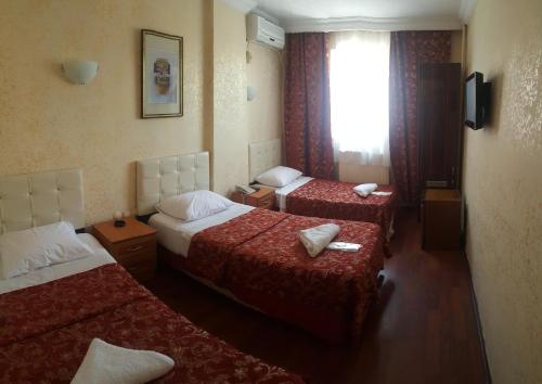 a hotel room with three beds and a window at Florin Hotel in Istanbul