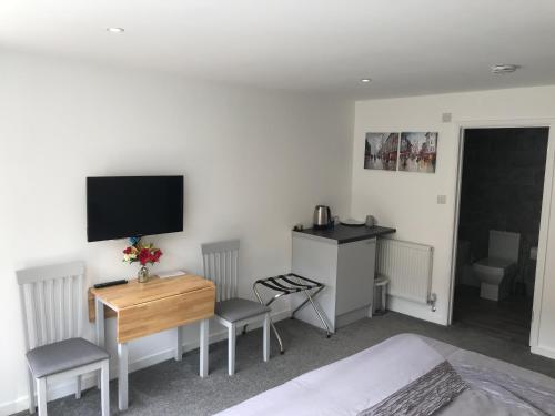 a bedroom with a bed and a desk and a television at Fornham Guest House in Chertsey