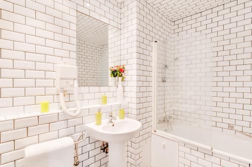 a white bathroom with a sink and a mirror at Grand Place Charbon Residence in Brussels