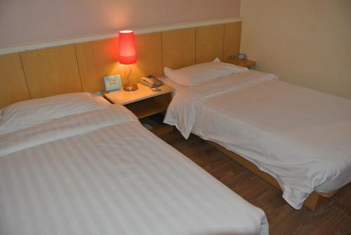 two beds in a hotel room with a lamp on a table at Beijing Sicily Hotel in Beijing