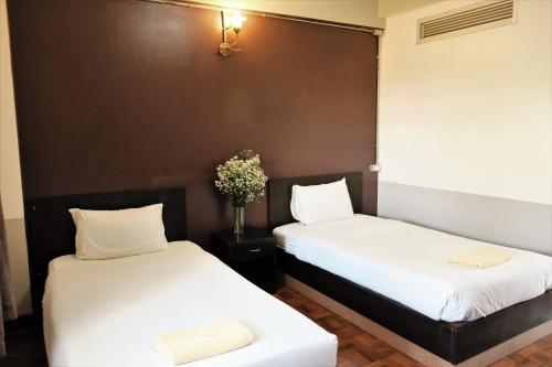 two beds sitting next to each other in a room at Puangpech Hotel Lampang in Lampang