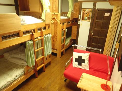a room with four bunk beds and a red chair at Yufuin Country Road Youth Hostel in Yufuin