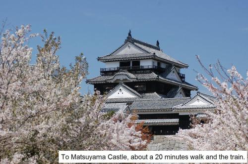 a large building with a tower with trees in front at Hotel Kajiwara in Matsuyama