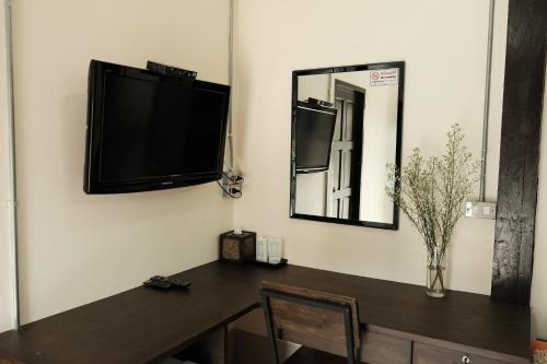 a room with a table and a television on a wall at Puangpech Hotel Lampang in Lampang