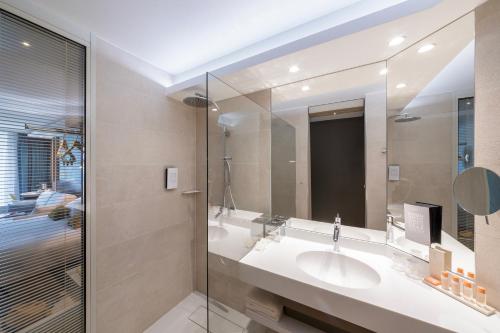 a bathroom with two sinks and a mirror at voco Strasbourg Centre - The Garden by IHG in Strasbourg