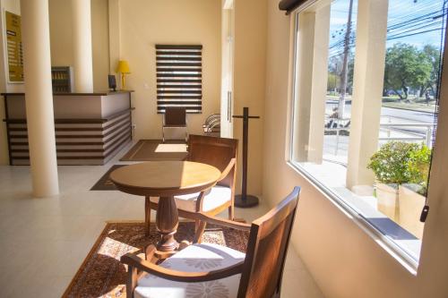 comedor con mesa, sillas y ventana en Hotel Marrocos en Pelotas