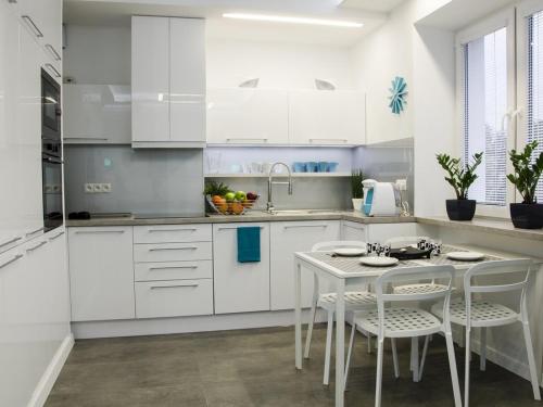a kitchen with white cabinets and a table and chairs at Apartament Skoczyńskiego 11a in Stalowa Wola