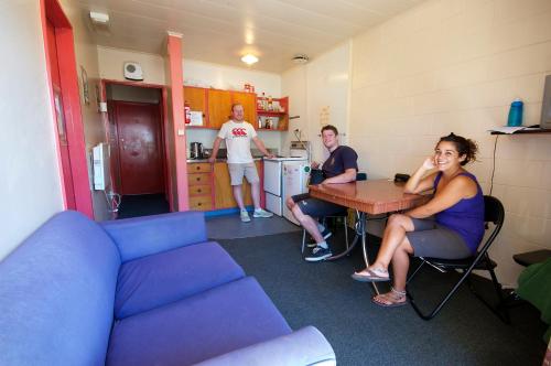 eine Gruppe von Personen, die an einem Tisch in einem Zimmer sitzen in der Unterkunft Southern Laughter Backpackers in Queenstown