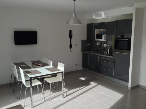 une cuisine avec une table et des chaises ainsi qu'une salle à manger dans l'établissement Les Portes de la baie, à Grand-Laviers