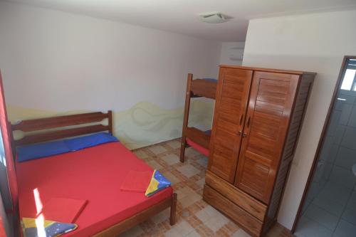 a small bedroom with a bed and a wooden cabinet at Brasil-Kite in Paracuru